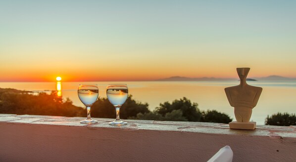 Vista al atardecer con dos vasos de agua y un florero en un alféizar.
