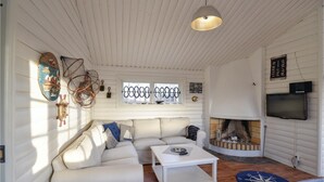 A cozy living room with a white sofa, a coffee table, a fireplace, and a TV mounted on the wall.
