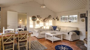 A cozy cabin interior with a dining area, a sofa, and a coffee table.