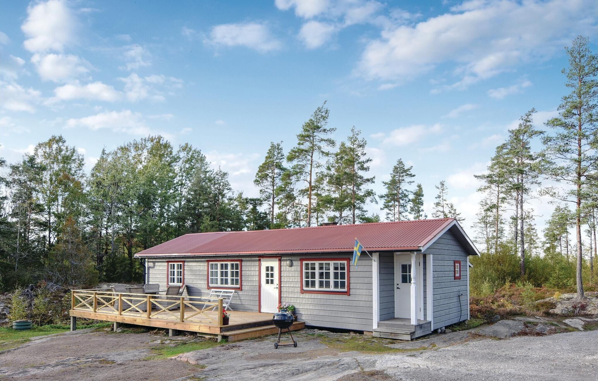 Une petite cabane avec un toit rouge, une véranda avec des sièges et un drapeau.