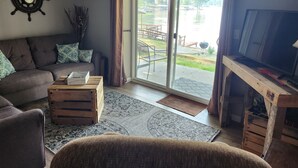 A living room with a sofa, a coffee table, a TV, and a view of a water body outside.