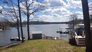 A lakeside property with a dock, a small shed, and a wooden deck.