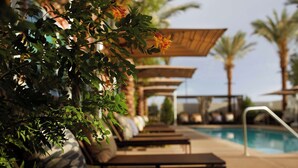 Un espace aménagé au bord de la piscine, avec des chaises longues, une pergola et une piscine.