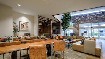 Un salón amplio con una gran mesa de madera, asientos cómodos y una pared decorativa de piedra.
