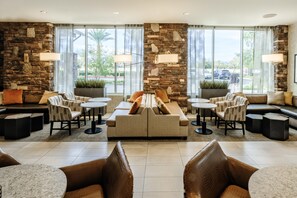 Een moderne lobby met een accentmuur van steen, zitgedeeltes en grote ramen.