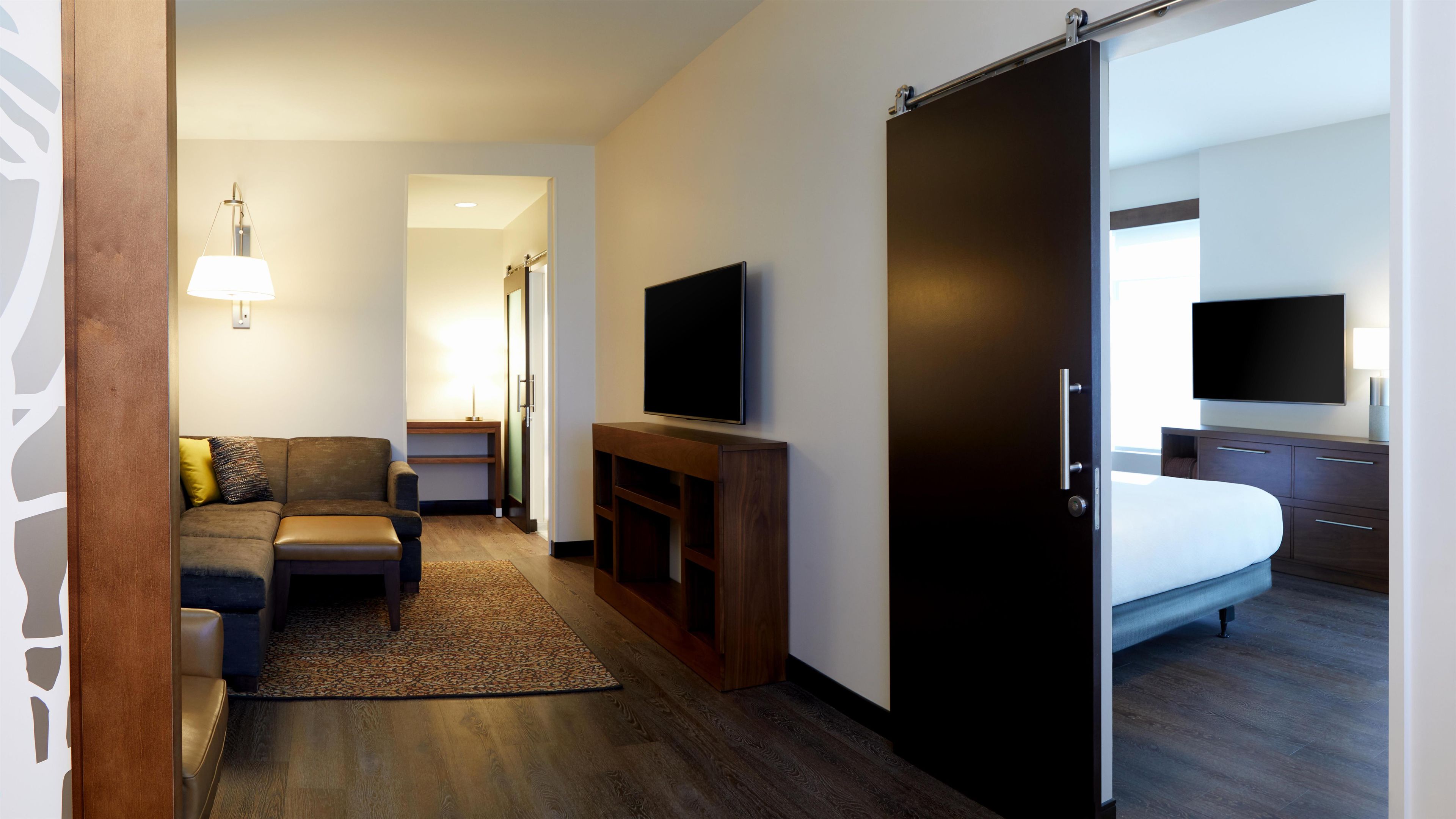 Ein Hotelzimmer mit einer Couch, einem Fernseher, einem Bett und einer Schiebetür.