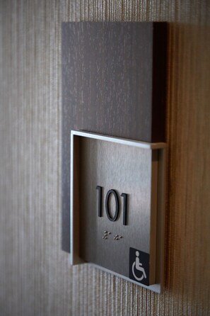 Gros plan d’une plaque indiquant le numéro de chambre, portant le numéro 101, et affichant le symbole d’accessibilité pour les personnes en fauteuil roulant.