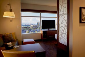 Une chambre d’hôtel dotée d’une grande fenêtre, d’un téléviseur à écran plat, d’un bureau et d’un coin salon confortable.