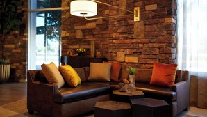 Un salon moderne avec un canapé en cuir, une table basse et un mur en pierre.