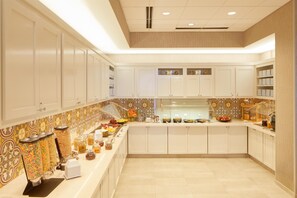 Una cocina moderna con armarios blancos, una isla central con alimentos y un revestimiento de pared decorativo.