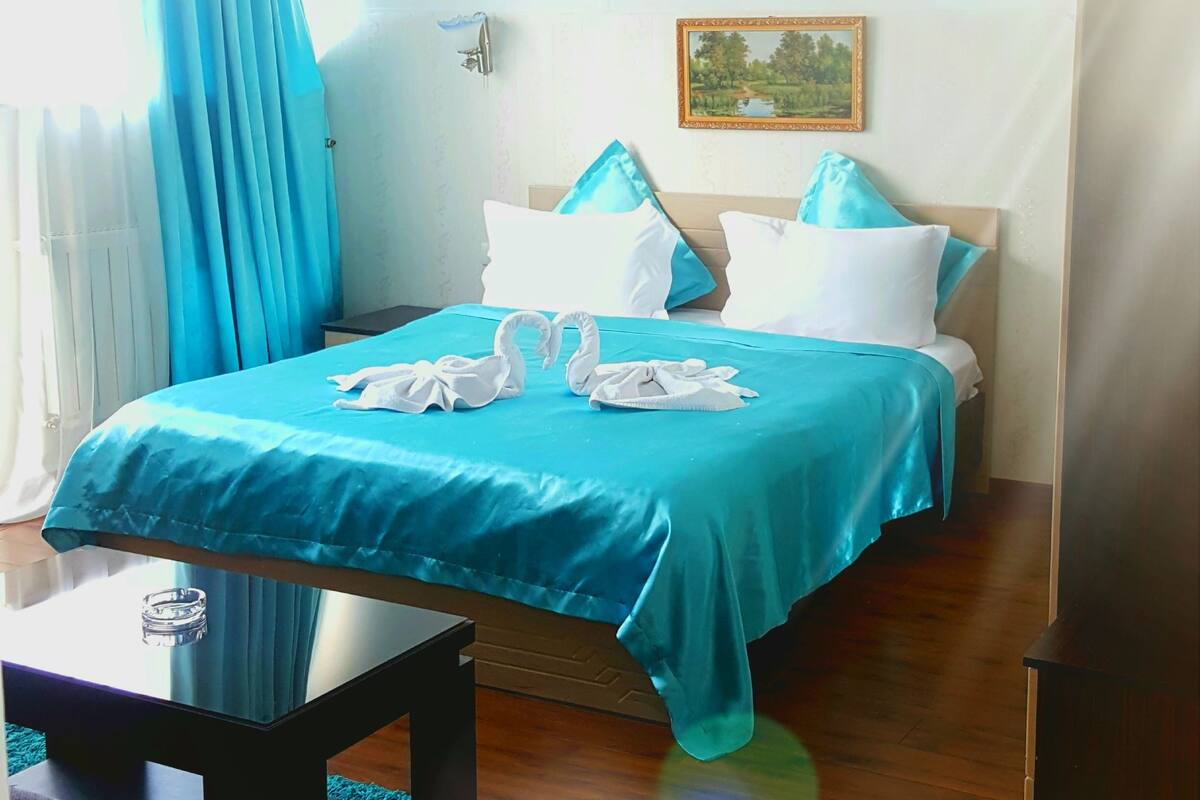 A hotel room with a bed, a small table, a chair, and a picture on the wall.