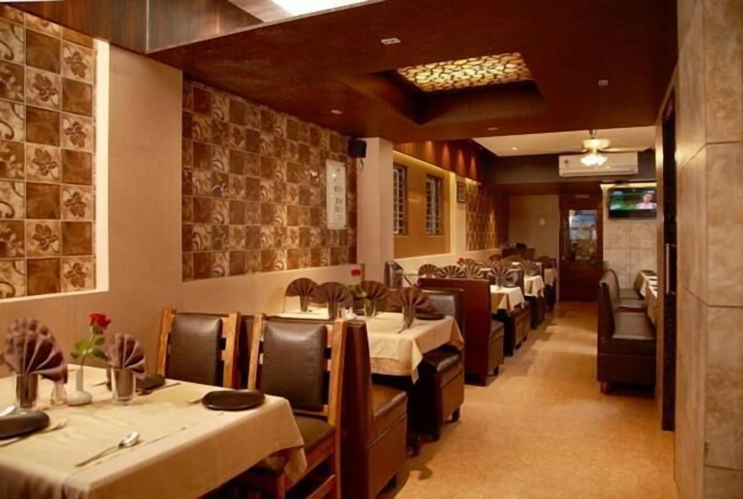 A restaurant with a long counter, multiple tables, and chairs.