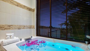 A spa tub with rose petals, a towel rack, and a window with blinds. - Sunny Banks - 4 Bed Private Pool Sea View Villa (Ko Samui)