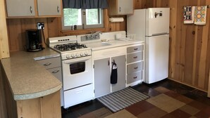 Una cocina compacta con armarios de madera, cocina a gas, refrigerador y cafetera.