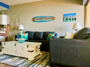 Relax in this stylish living room with a black leather sofa, vintage-style chest, and patterned rug.