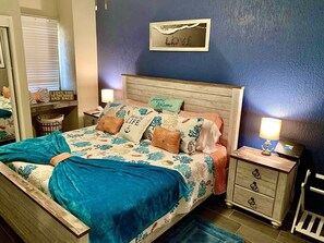 Ein Schlafzimmer mit Bett, Nachttischen, einem Schminktisch und einer Wand mit der Aufschrift 'LOVE'.
