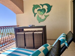 Enjoy the ocean view from this balcony with a wicker table and comfortable seating.
