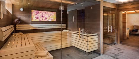 A modern spa room with a wooden bench, glass walls, and a television screen.
