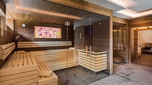 Ett modernt spa-rum med en träbänk, glasväggar och en tv-skärm.
