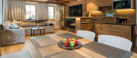 A modern kitchen with wooden cabinetry, a built-in microwave, and a dining area with a table set for four.