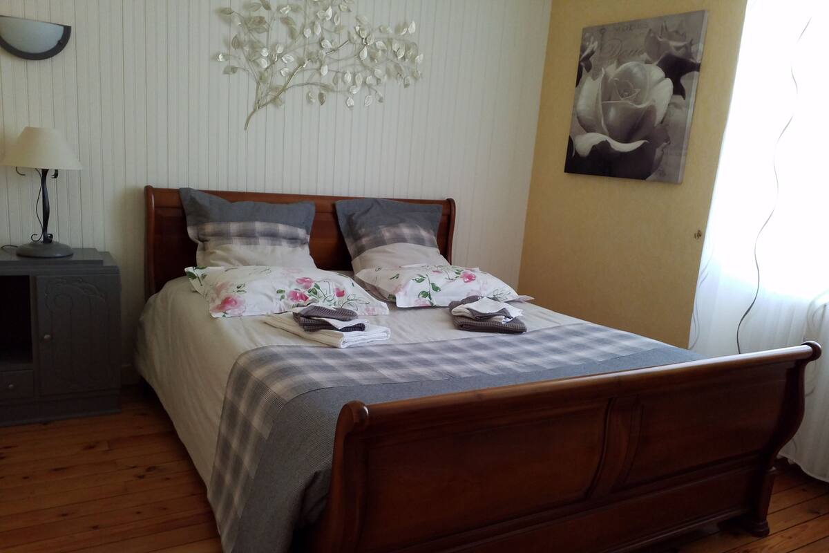 Una cama bien hecha con ropa de cama floral, un cabecero de madera y una mesita de noche con una lámpara.