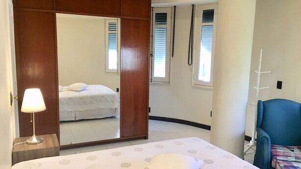 Une chambre à coucher avec un lit, une lampe de chevet, une armoire et une chaise.