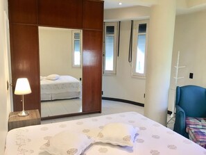 Quarto com cama, luminária de cabeceira, guarda-roupa e uma cadeira.
