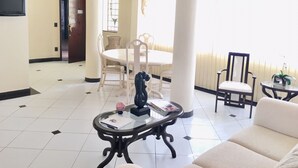 Un vaste espace de vie comprenant une table à manger, des chaises, un canapé et une table basse agrémentée d’objets décoratifs.