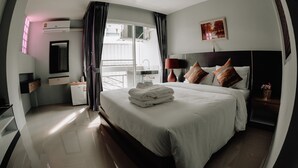 A modern hotel room with a large bed, a small desk, a window with curtains, a bedside table with a lamp, and a painting on the wall. - Step One at Bangkok (Bangkok)