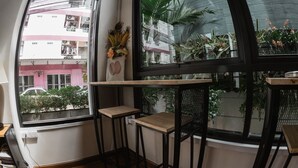 A corner of a room with a large window, a small wooden table, and a chair. - Step One at Bangkok (Bangkok)