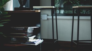 A room with a wooden floor, a desk with a lamp, a bookshelf, and a view of greenery through a window. - Step One at Bangkok (Bangkok)