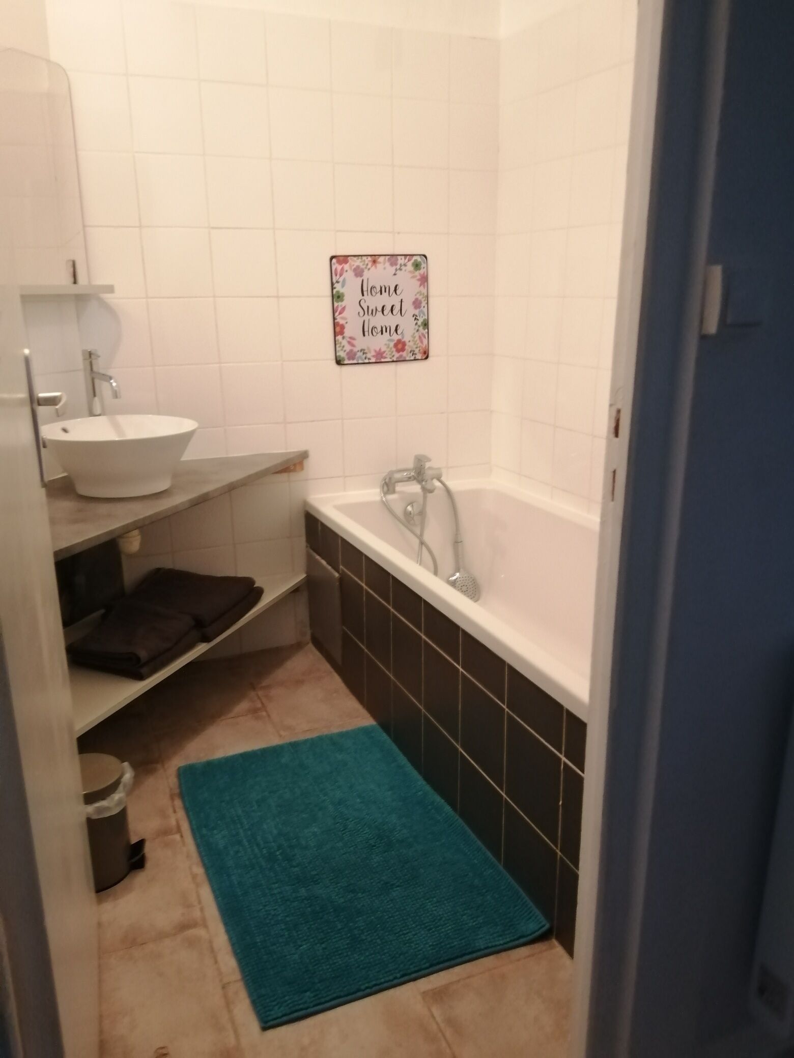 A small bathroom with a white sink, a bathtub, and a blue rug.