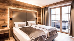 Un dormitorio moderno con una cama grande, paneles de madera, un ventanal corredero a un balcón y una mesita de noche.