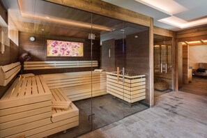 Ein moderner Wellnessraum mit einer Holzbank, Glaswänden und einem Fernsehbildschirm.