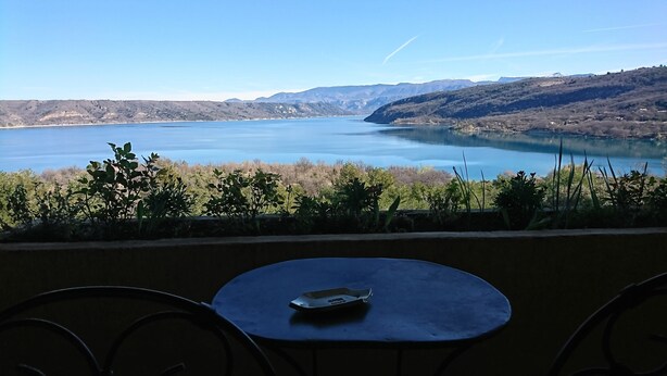 Una mesa con un control remoto, con vistas a un lago y montañas al fondo.