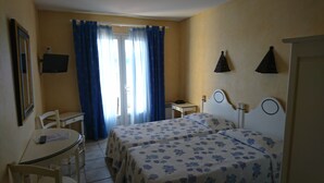 Habitación de hotel con dos camas, un escritorio, una silla y una ventana con cortinas.