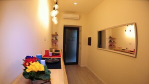 A hotel hallway with a wooden reception desk, a mirror, and a door leading to a room. - B&B Guest Armonie (Torre del Greco)