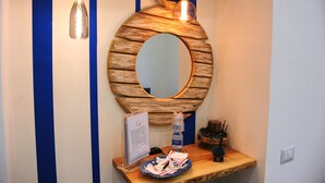 A wooden-framed mirror with a round shape, a small wooden table with a tray, and a bottle of water. - B&B Guest Armonie (Torre del Greco)