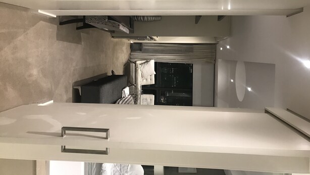 Ett modernt kök med en vit bänkskiva, en inbyggd ugn och ett fönster med utsikt över en stadssiluett i nattljus.