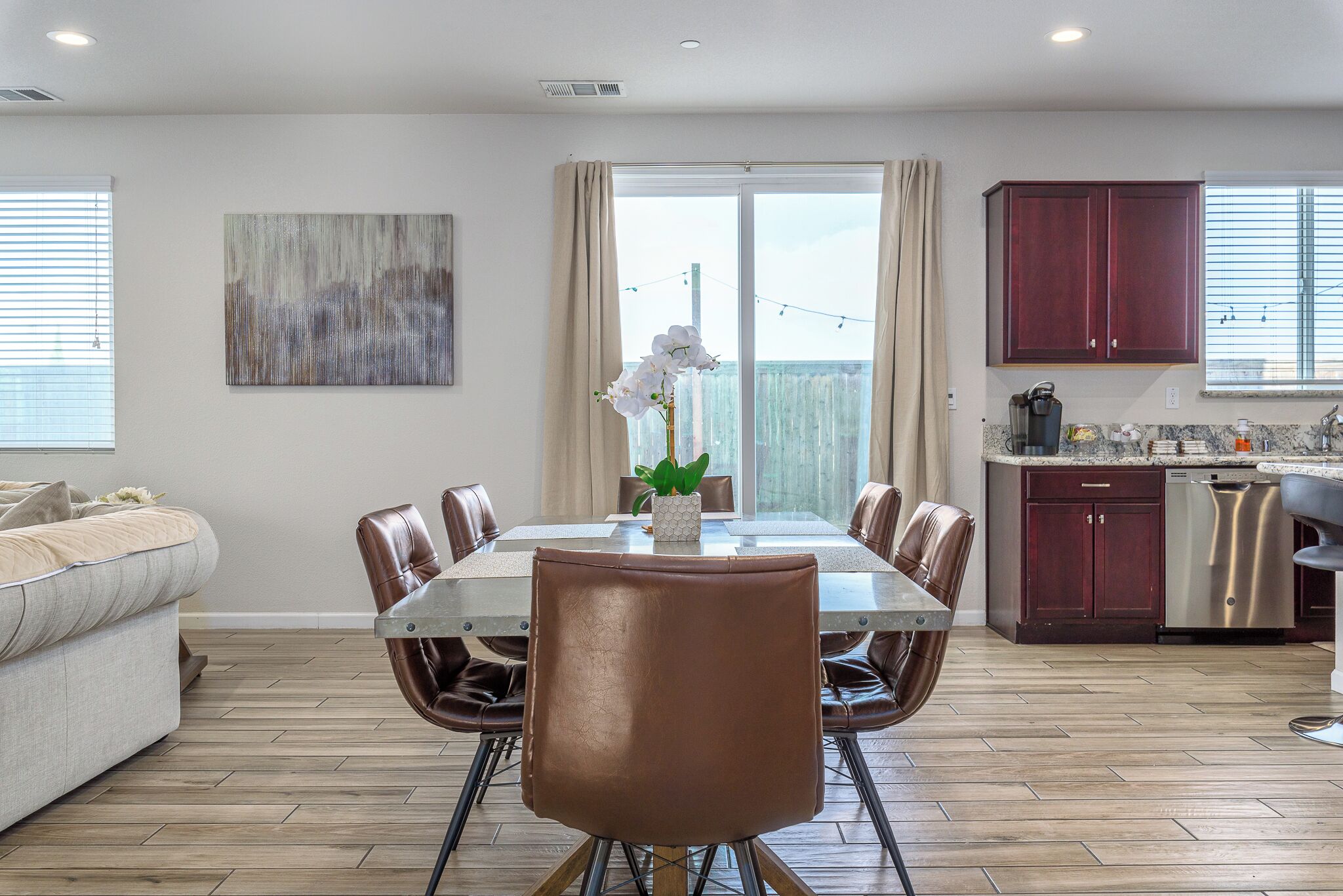 Un espace repas moderne avec une table en verre, des chaises en cuir et une orchidée en pot.