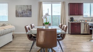 Un comedor moderno con una mesa de vidrio, sillas de cuero y una orquídea en maceta.