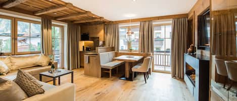 A spacious living area with a wooden ceiling, a dining table, and a fireplace.