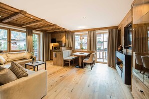 A spacious living area with a wooden ceiling, a dining table with chairs, a sofa, and a fireplace.