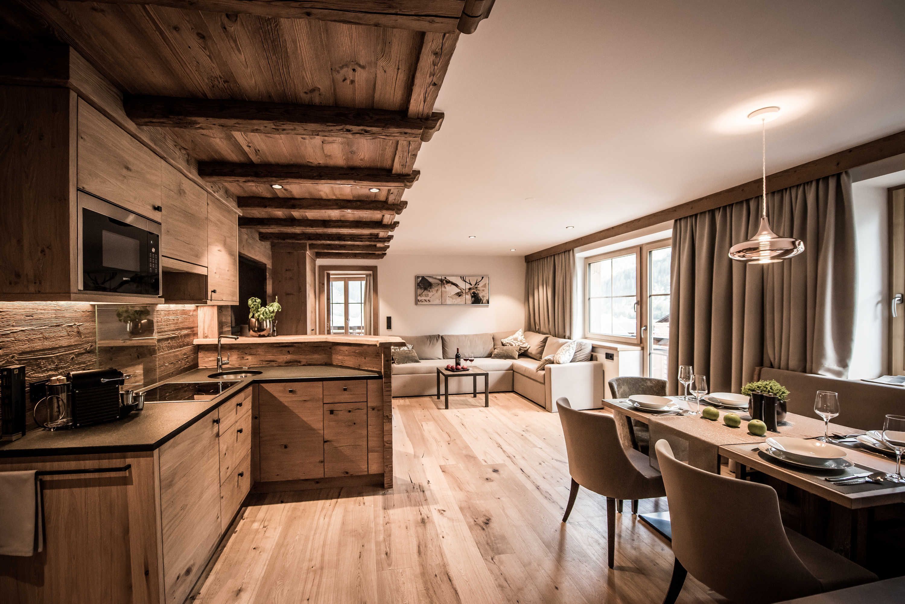 A modern kitchen with wooden beams, a built-in microwave, and a dining area with a table set for two.