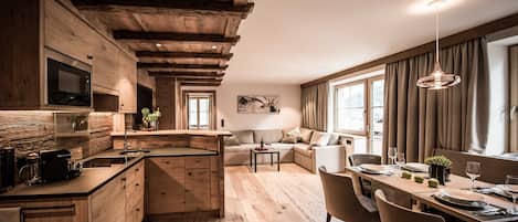 A modern kitchen with wooden beams, a built-in microwave, and a dining area with a table set for two.
