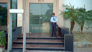 A reception area with a sign labeled "Reception," a man standing in front of a glass door, and steps leading up to the entrance.