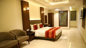 A hotel room with a bed, a sofa, a nightstand, a mirror, and a TV.