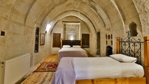 A rustic room with a vaulted ceiling, a wooden bed, a radiator, and a wooden wardrobe. - Kookaburra Hotel (Nevsehir)