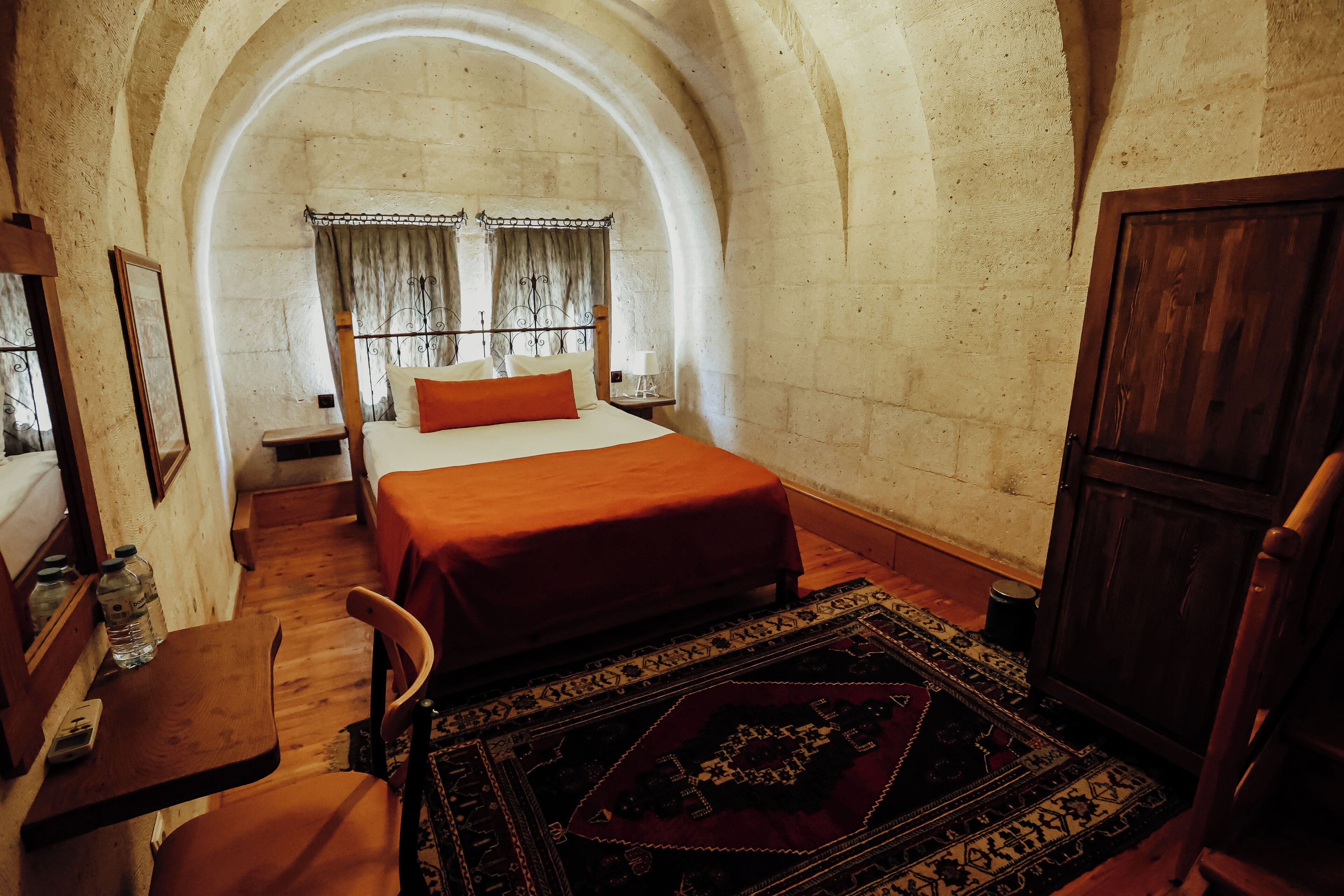 Une pièce avec un lit, des meubles en bois, un tapis et un plafond en arc de cercle.