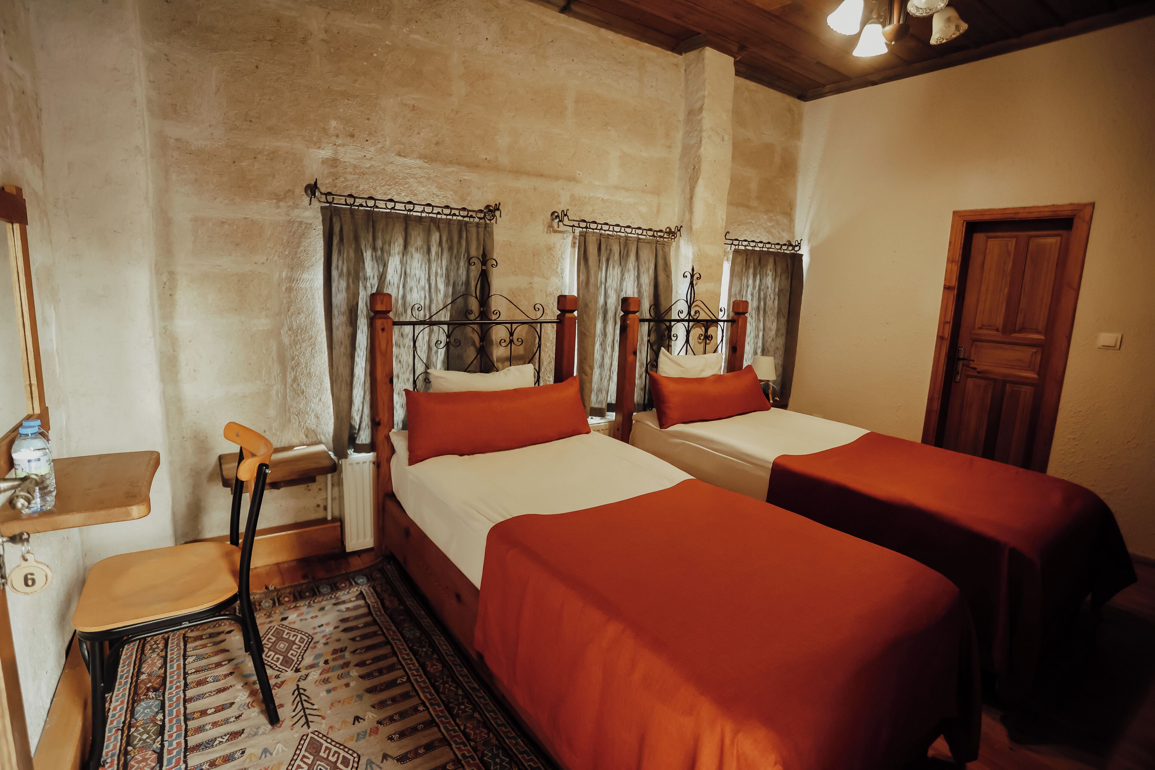 A room with two beds, a wooden chair, a small table, and a door.